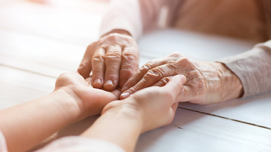 An elderly person holding the hands of a younger person