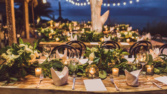 A table decorated with candles, plants, napkins, and cutlery.