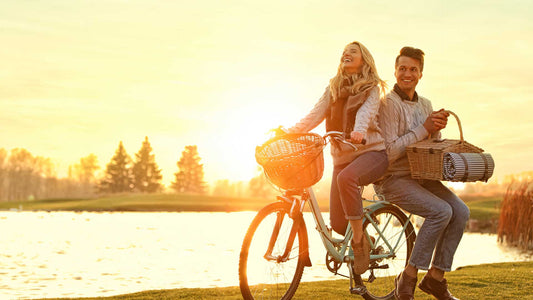 Couple on a bicycle holding a picnic basket