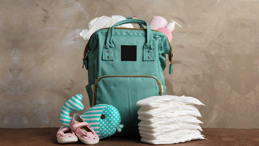 Bag with diapers and baby accessories on wooden table